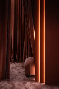 A modern interior design featuring dark velvet upholstery with orange neon lights.