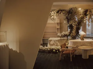 A living room with modern interior design featuring a display area with cotton flowers, a wooden chair, and a round table.