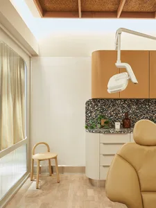 Medical office with white walls and natural wood accents, featuring a patient chair and medical equipment.