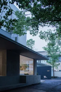 A modern outdoor space featuring a building with large glass windows and concrete walls.