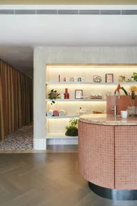 A spa interior featuring terrazzo countertops and marble accents, with a circular counter, shelves displaying spa products, a