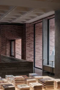 A bookstore interior with brick walls, concrete accents, and large windows.