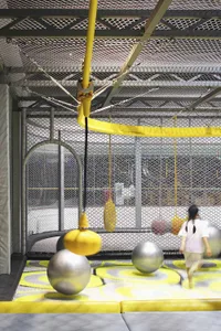 An industrial-style indoor playground with metal bars, foam spheres, and rubber flooring