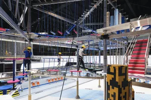 An industrial-styled playground with a metal rope course overhead