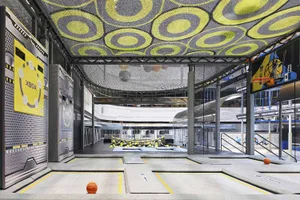 Indoor sports facility with industrial design features, concrete flooring, and mesh ceiling