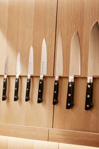 A series of knives mounted vertically on wooden display units, showcasing a selection of knives for kitchen use.