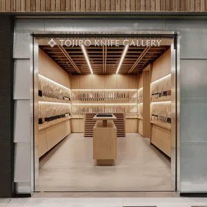 A well-lit, contemporary storefront displaying a collection of knives on wooden shelves and walls.