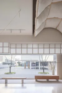 A minimalist concrete interior space featuring modern furniture and large windows.