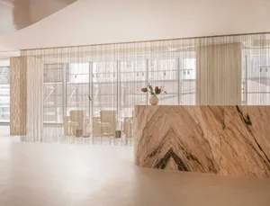 A minimalist reception desk with a marble countertop and a vase with flowers.