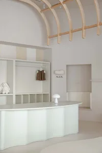 A minimalist retail storefront with wooden arches and a white curved reception desk.