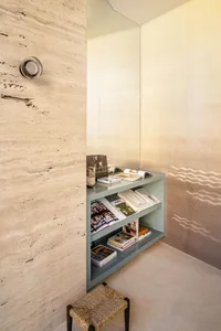 Modern-style concrete bookshelf with books and a wicker stool.