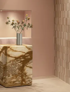 A modern marble table featuring a vase of flowers in a silver vase against a pink wall and beige tiled floor.
