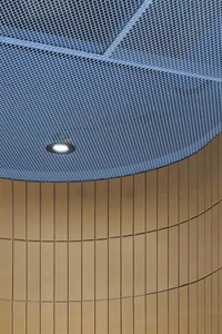 A close-up of a blue metal grid ceiling with a recessed light fixture.