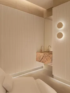 Modern bathroom featuring a marble sink vanity and concrete textured walls with soft lighting.