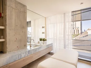 Modern bathroom featuring marble countertops and concrete walls.