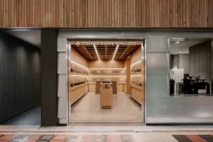 A modern retail storefront with wooden interior design and a display of knives under bright lighting.