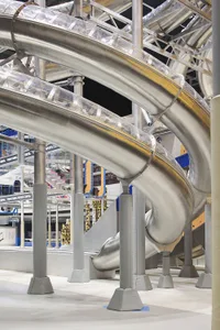 Metallic slide structure with curved pathways and transparent barriers