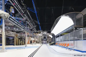 A modern sports center with metal beams, glass walls, and plastic tubing structures