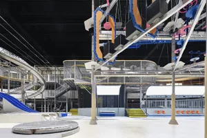 A large, indoor amusement area featuring metal structures, plastic playground equipment, and composite materials designed for