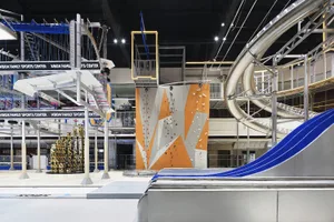 An industrial sports center with a climbing wall, slides, and trampolines.
