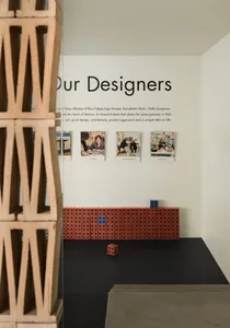 Interior image of a brick-themed architectural design exhibition with photographs of designers and a patterned setup of brick