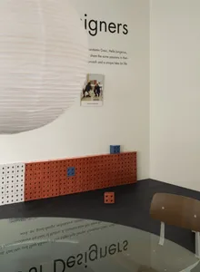 極簡室內空間，牆面由小紅磚砌成，搭配白色球形燈具與木質椅子。