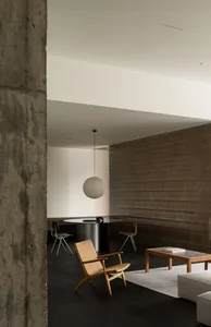 A minimalist living room featuring a concrete wall, wooden floor, and bamboo furniture.