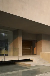 Concrete staircase with glass railing and metal railings, leading up to a modern building entrance.
