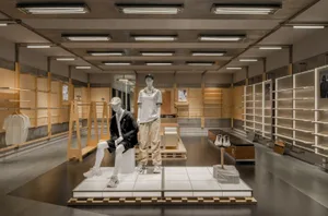 Modern retail store interior with minimalist design, featuring wood materials, and a focus on clothing racks and mannequins.