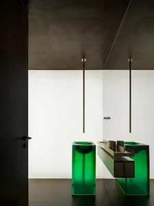 Industrial-style bathroom with green glass sinks and minimalist design.