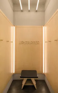 Modern minimalist clothing retail store with wooden walls and illuminated signage.