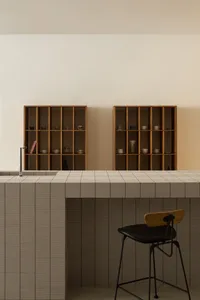Modern minimalist kitchen with a tiled countertop and wooden shelves.