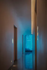 Modern hotel lobby with concrete walls and floors, featuring a waterfall in the background.