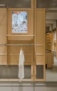 A retail shop interior featuring wooden shelves and a hanging shirt.