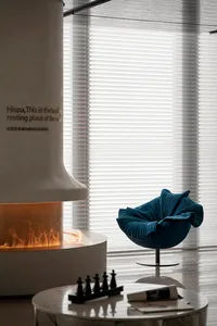 Modern living room interior with textured concrete fireplace and blue upholstered chair.