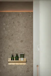 A minimalist bathroom showcases a concrete shelf with various toiletries.
