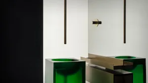 A sleek, modern bathroom with a glass sink and brass fixtures.