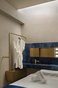 A modern bathroom with marble accents, featuring a white robe hanging and a sink with a mirror.