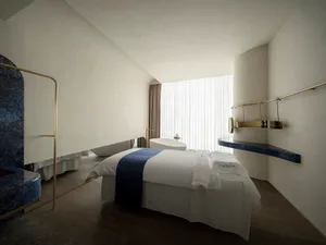 Modern bedroom with white walls, a wooden floor, and a marble bed.