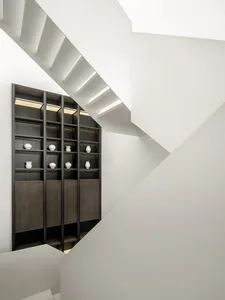 A modern staircase with white concrete steps and black wooden railings.