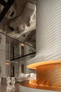 A modern living room featuring a metallic fireplace, concrete cylindrical columns, and a high-contrast ceiling.