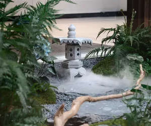 A serene Japanese garden featuring a stone lantern and various plants.