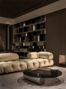 Modern, minimalist living room featuring a leather sofa, glass coffee table, and wooden shelving.