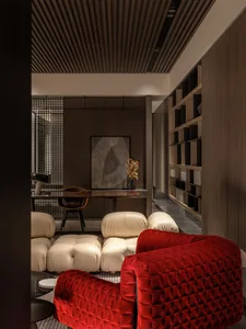 A modern living room with a red couch, white poufs, and wooden shelves