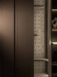 A modern metal pegboard closet storage system with adjustable pegs for organizing clothes and accessories.