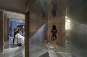 A modern hair salon with glass, metal, and brick walls.