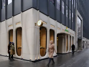 A modern Rolex storefront with concrete exterior and golden accents.