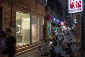 繁忙的街景，建築由磚、玻璃與金屬構成，搭配機車與霓虹燈招牌。