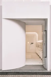 A modern minimalist storefront with glass and concrete elements.