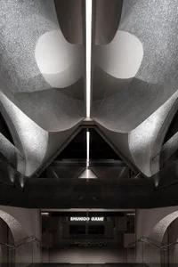 A modern restaurant with metallic finishes and geometric lighting fixtures.